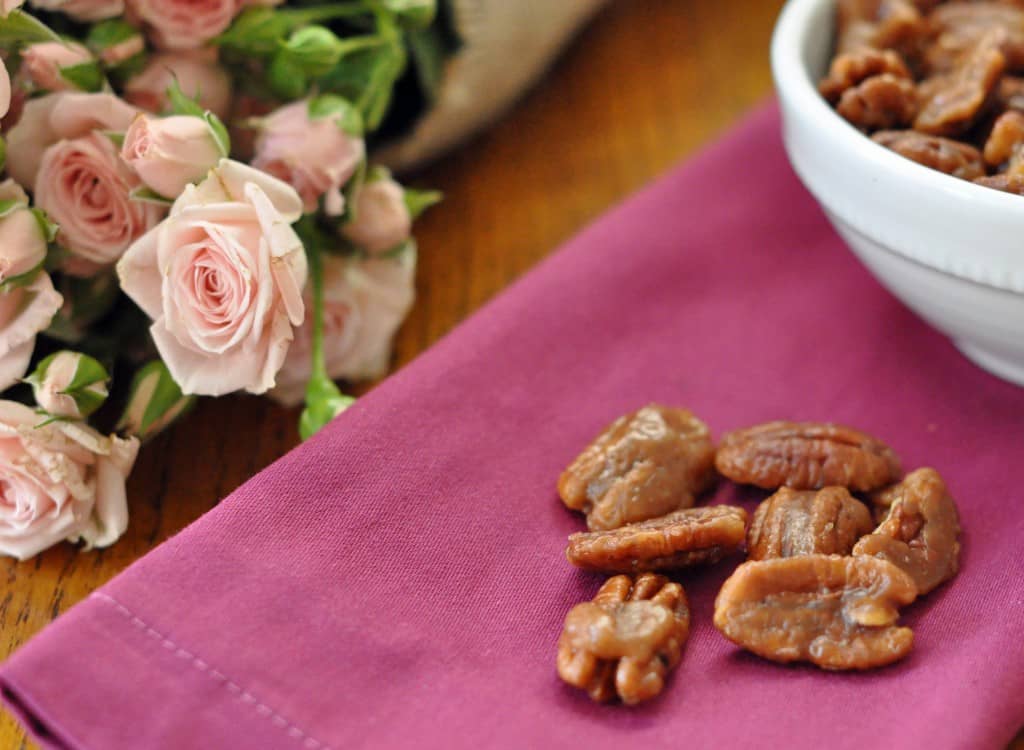 A white dish filled with candied pecans (caramelized pecans)