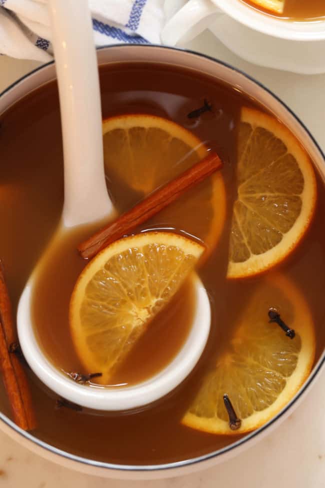 A white pot filled with hot mulled apple cider.