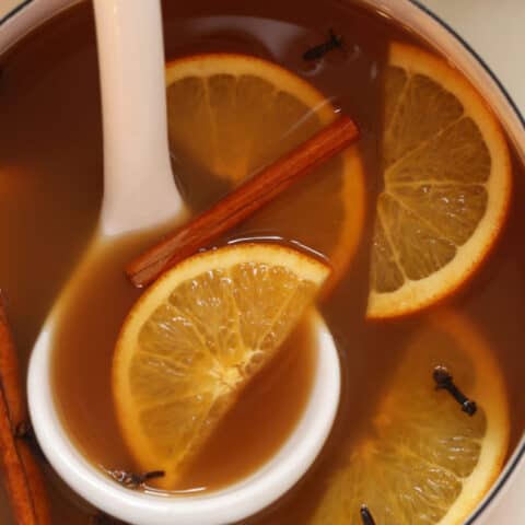 A white pot filled with Mulled Apple Cider.