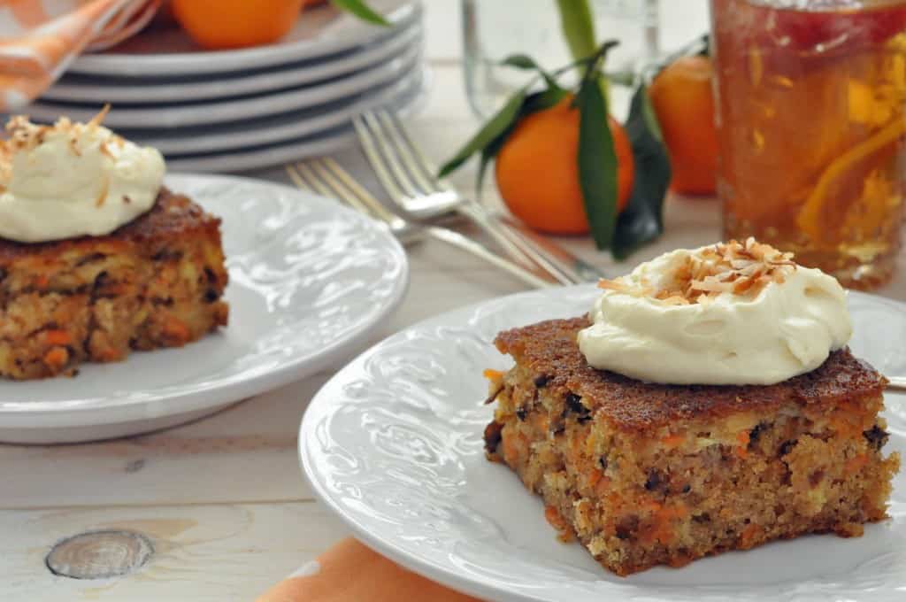 Two white plates with carrot cake squares on them.