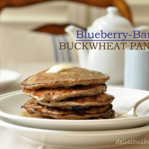 A white plate filled with a stack of Blueberry Banana Buckwheat Pancakes.