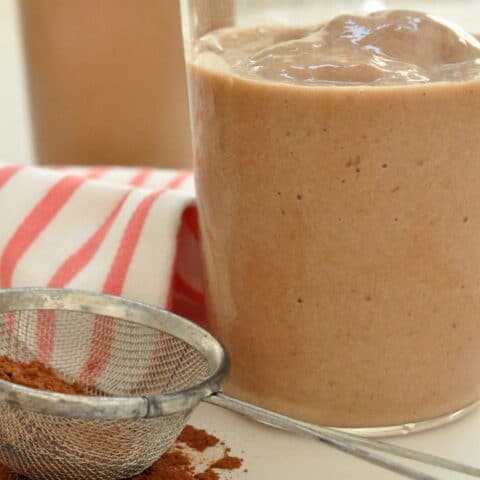 Two clear drinking glasses filled with chocolate banana smoothie.