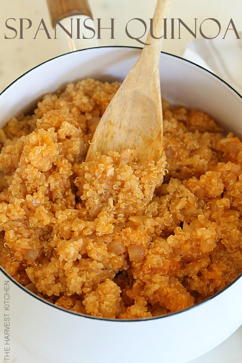 A white pot filled with cooked Mexican quinoa. A wooden spoon rests in the pot.