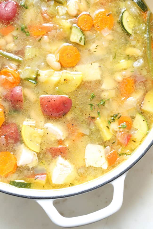 A white pot filled with French chicken vegetable soup (Soupe au Pistou).