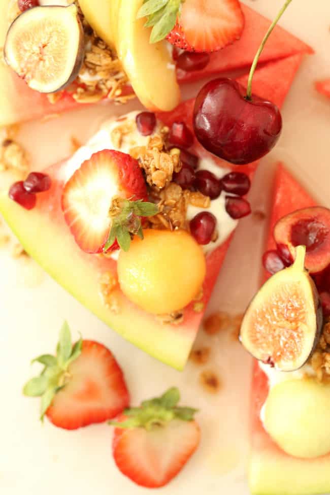 Slices of watermelon pizza with yogurt and slices of fruit on top.