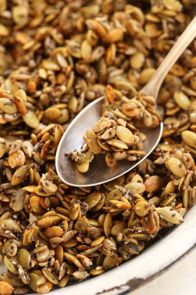 A white dish with honey roasted pumpkin seeds.