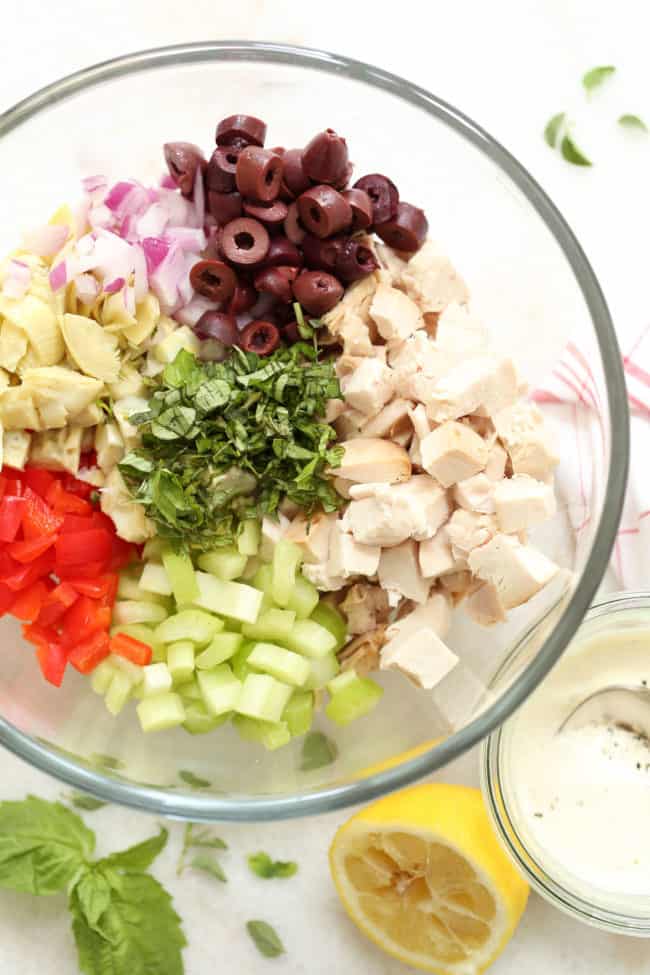 A clear glass mixing bowl filled with Italian salad.