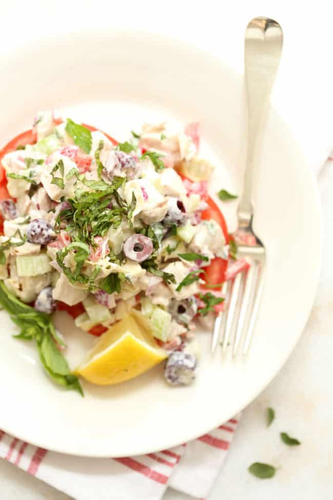 A white plate filled with chopped salad ingredients on tomato slices.
