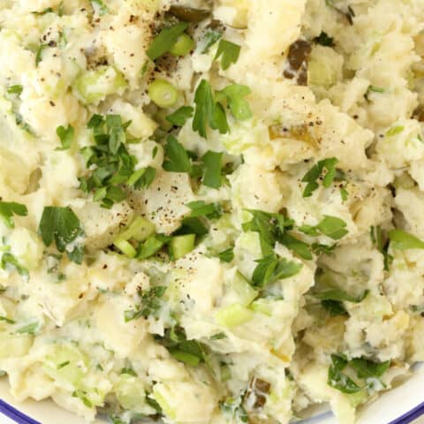 A white bowl filled with Dill Pickle Potato Salad.