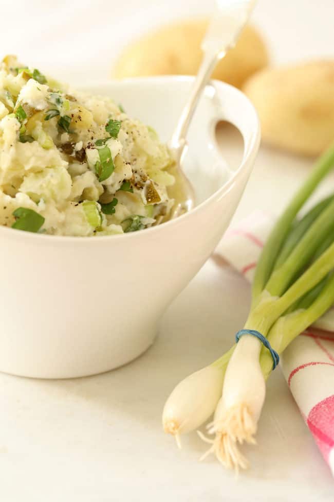 A white bowl filled with a side dish. A tablespoon rests in the bowl.