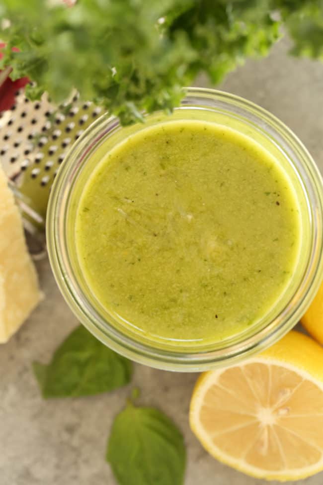 A clear glass jar of lemon herb vinaigrette.