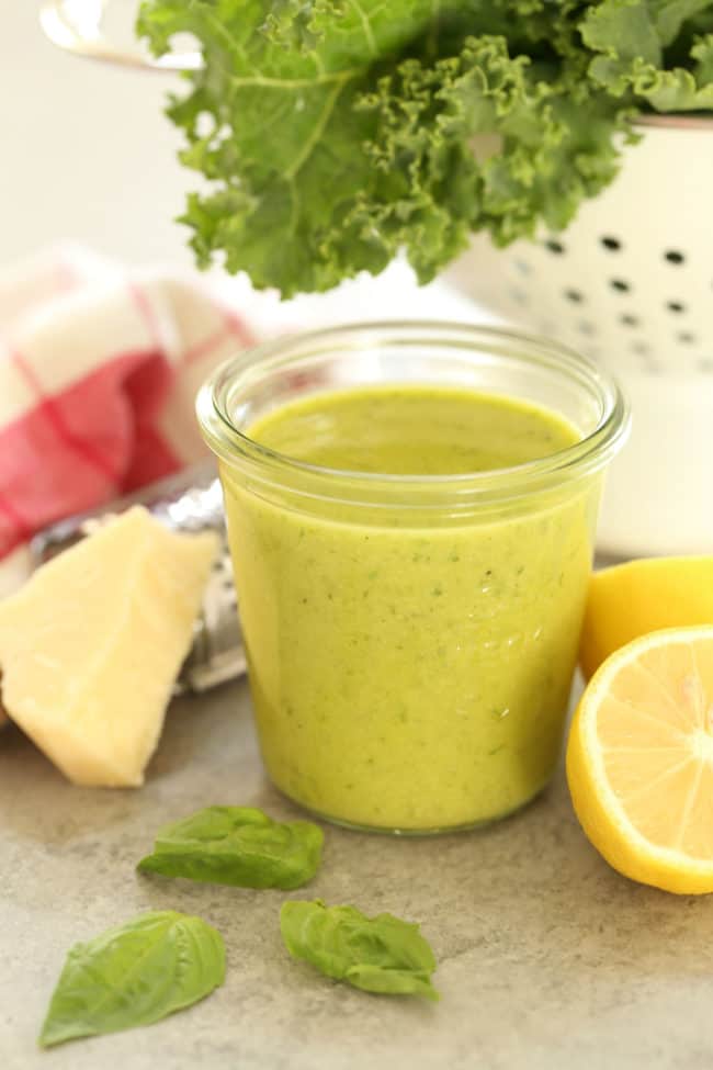 A clear glass jar of lemon basil salad dressing.