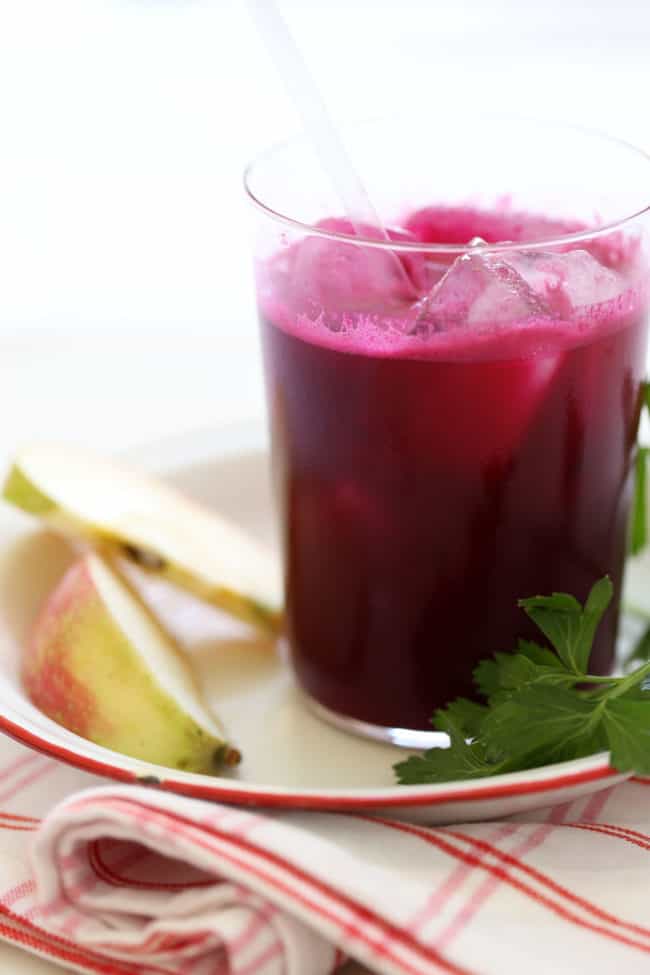 A clear glass filled with beet ginger juice drink.