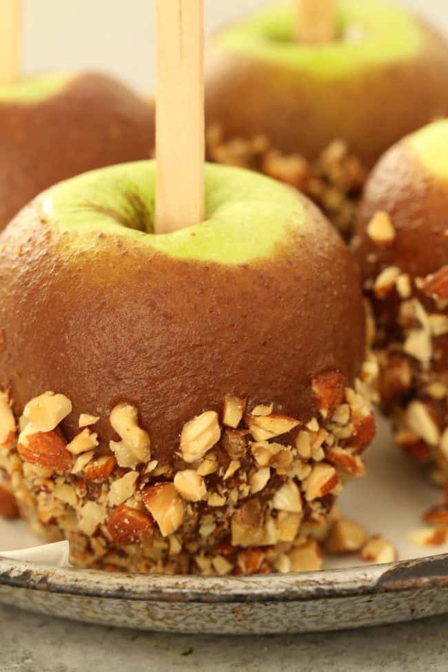 Four healthier caramel apples on a plate.