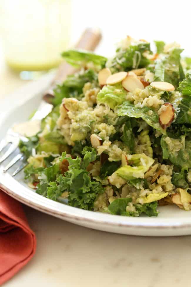 A white plate of tossed greens with a fork sitting next to it.