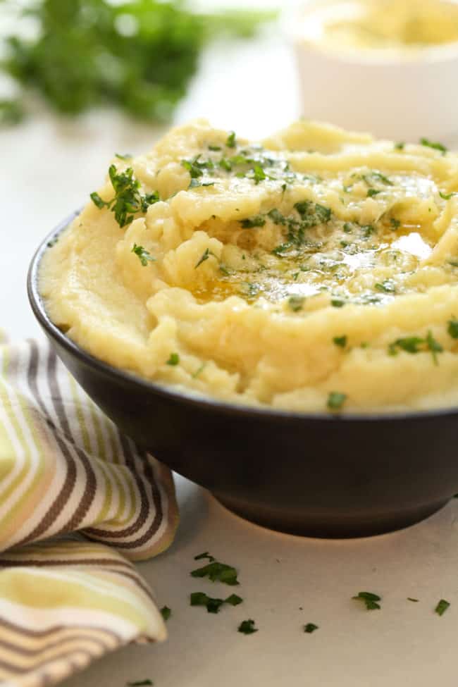 A dark brown bowl filled with Mashed Sweet Potatoes.
