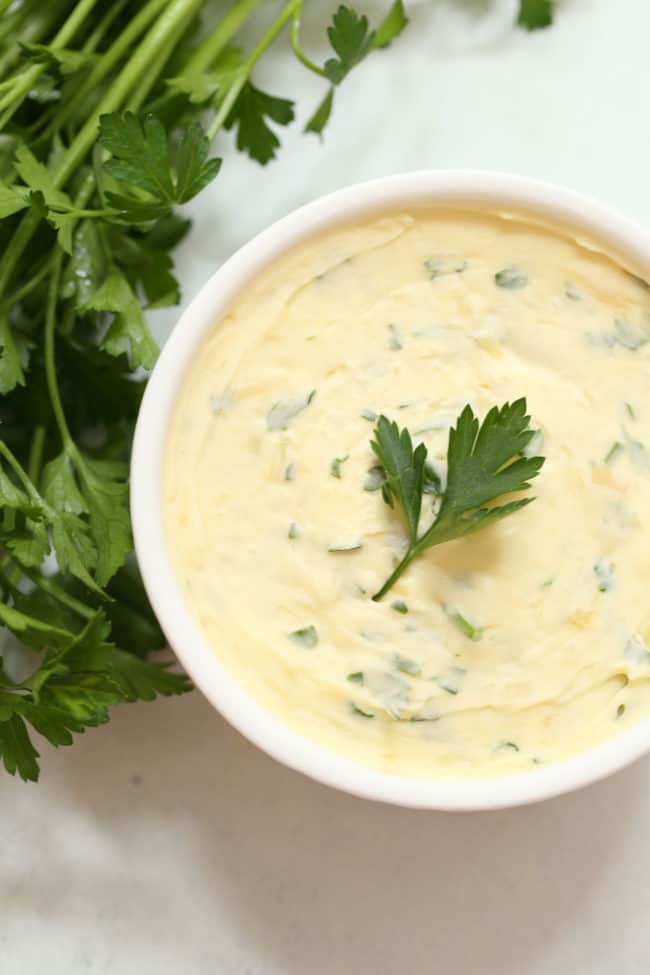 A ramekin filled with roasted garlic parsley butter for mashed sweet potatoes. 
