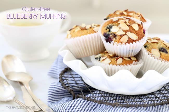 A white dish filled with blueberry muffins. A blue and white striped dish towel sits under the dish.