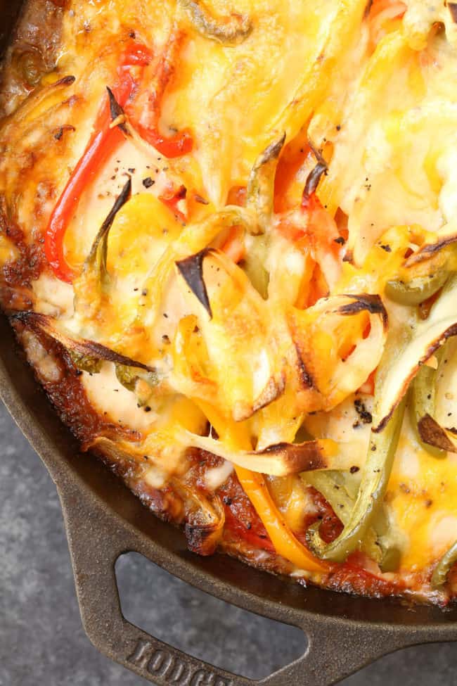 A black skillet filled with cooked poultry and vegetables.