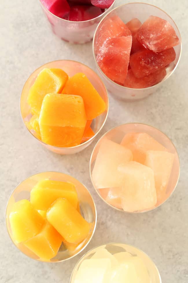 drinking glasses filled with fruit juice ice cubes