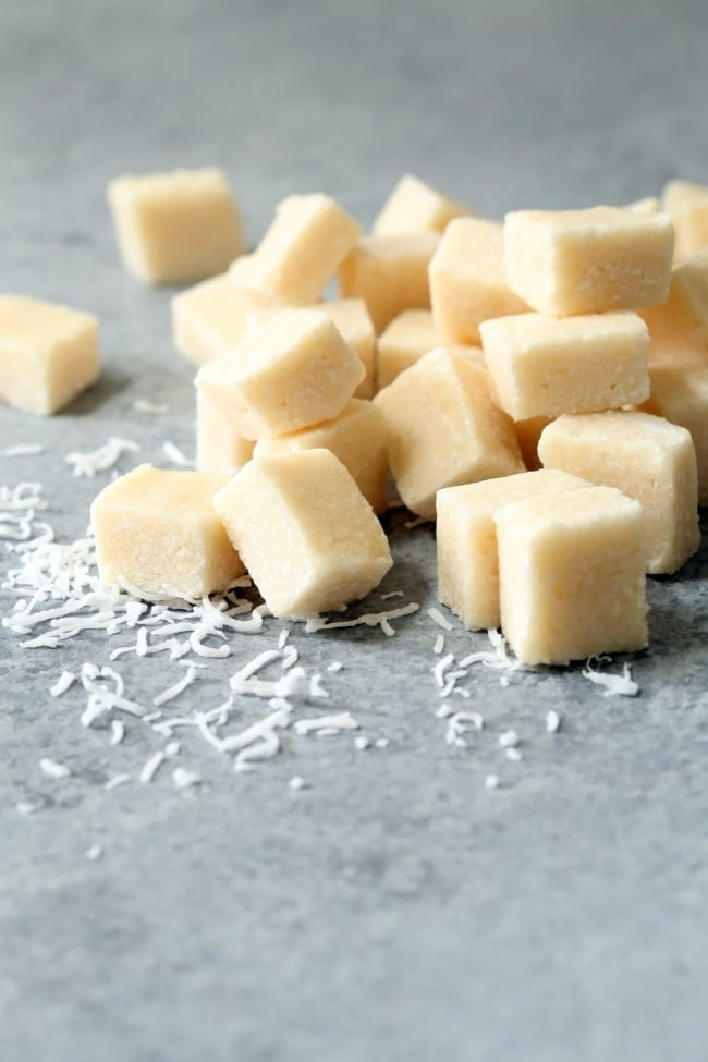 Squares of frozen coconut bites set on a gray board.