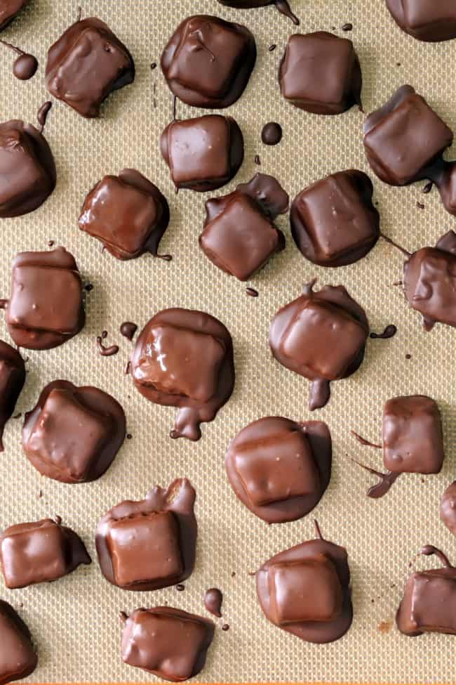 A silpat covered with square chocolate pieces with melted chocolate