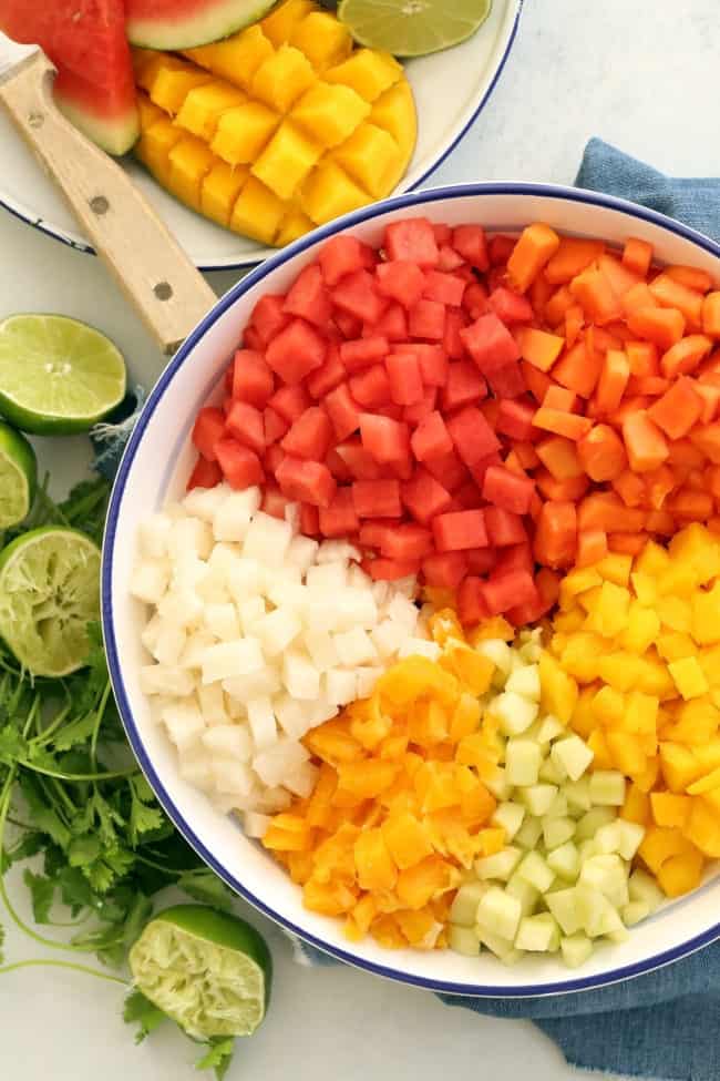 A white bowl of chopped melon and mango salad.