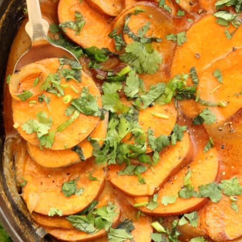 A black cast iron skillet filled with Scalloped Sweet Potatoes.