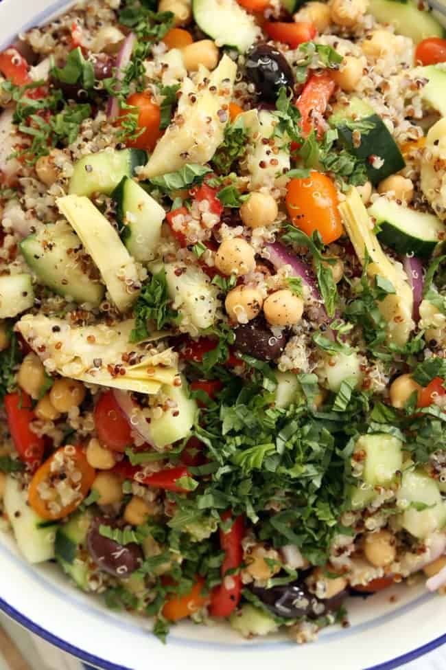 A large white bowl filled with a Mediterranean quinoa salad.