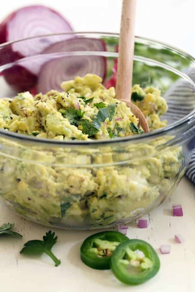 A clear glass bowl of mashed eggs with avocado.