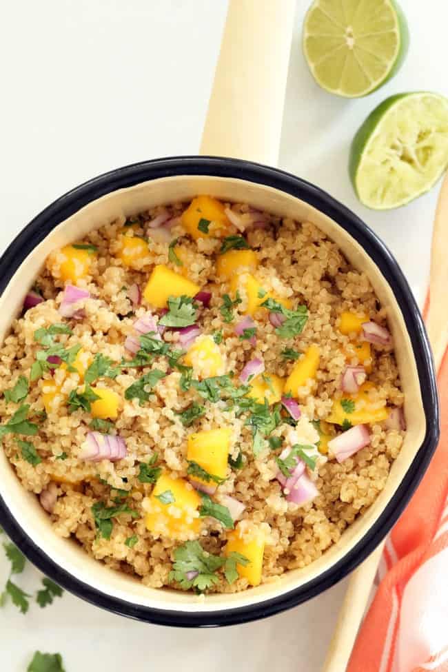 A white pot filled with quinoa with mango salsa.