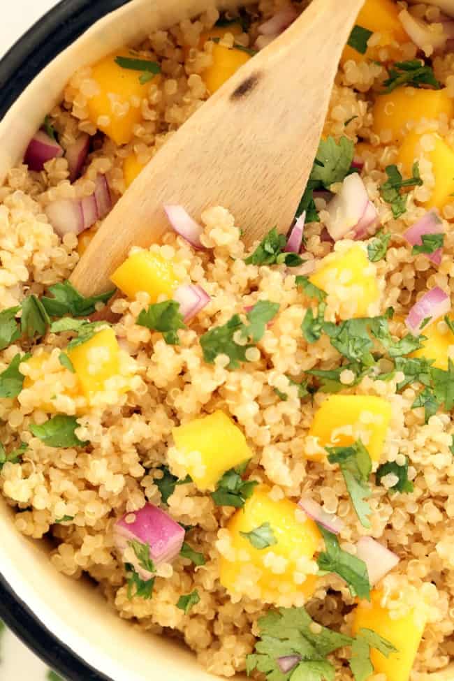 A white pot of quinoa with mango salsa for a quinoa side dish.