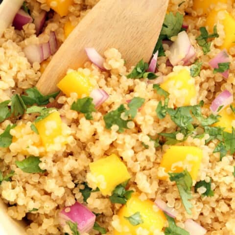 A white pot of cooked quinoa with mango.