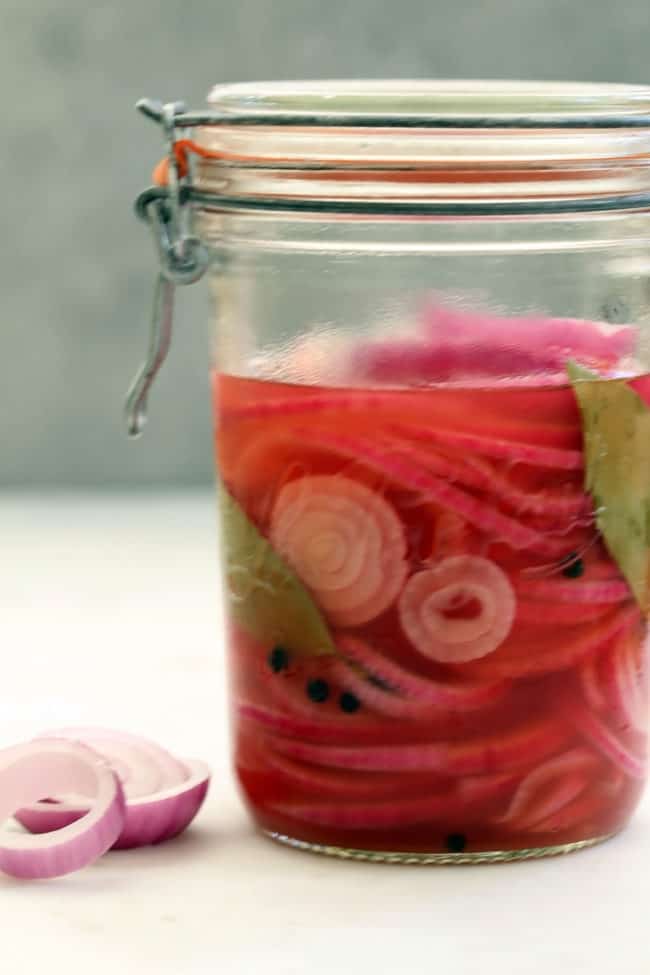 A clear glass jar filled with pickled onions.