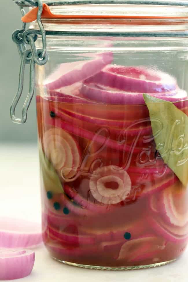 A clear glass mason jar filled with slices of pickled onions.