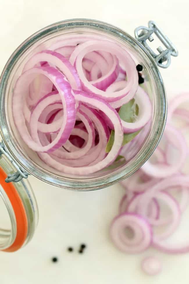 A clear glass mason jar filled with slices of allums.