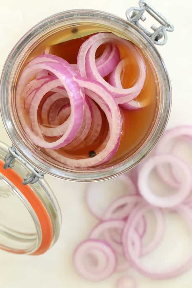 A clear glass mason jar filled with pickled onions.