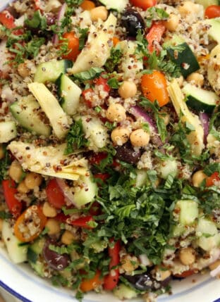 A large white bowl filled with Mediterranean quinoa salad.