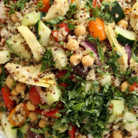 A large white bowl filled with Mediterranean quinoa salad.