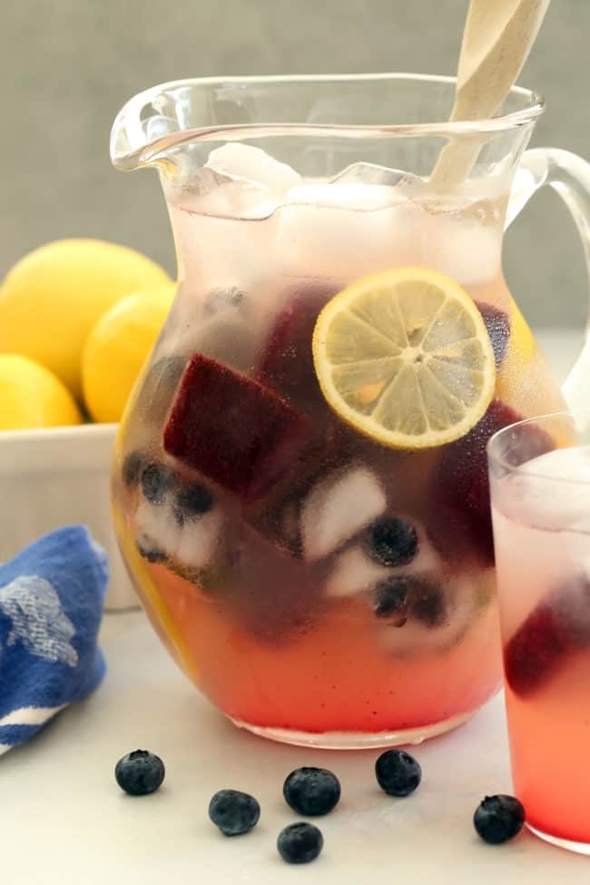 A clear glass pitcher filled with lemonade.
