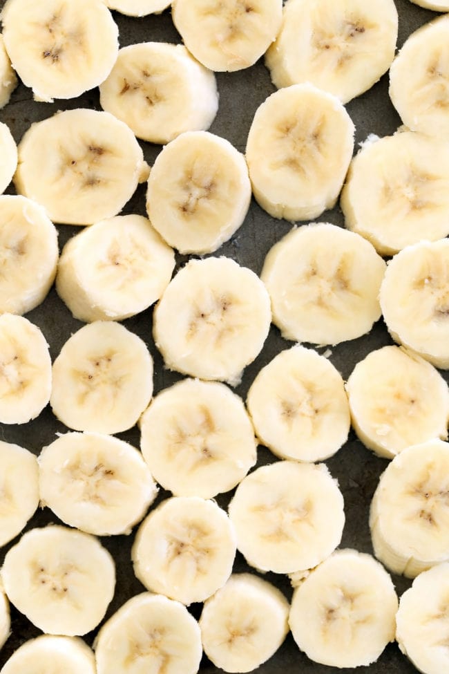 Several slices of frozen banana on a cookie sheet.