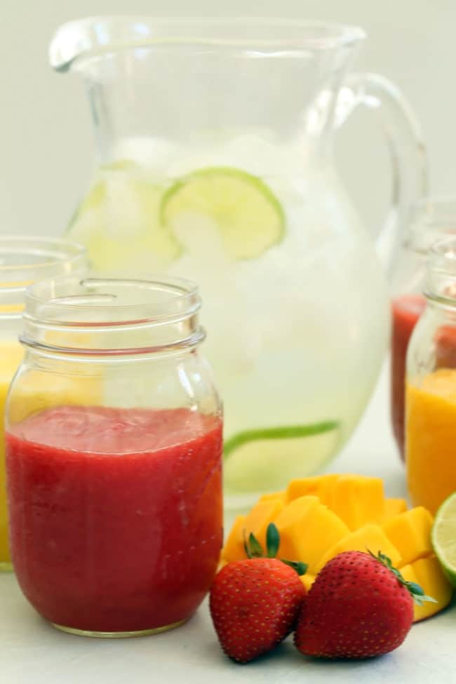 Several clear glass mason jars with fresh fruit drink.