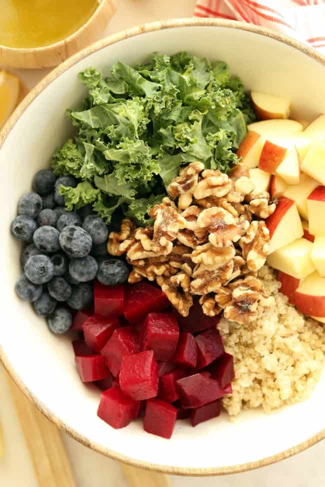 A white bowl of kale quinoa salad ingredients.