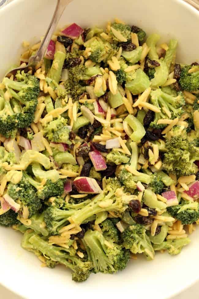 A white bowl of chopped broccoli raisin salad.