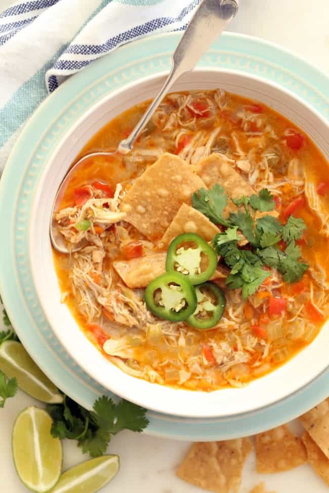 A white bowl filled with chicken chili without beans. A spoon rests in the bowl.