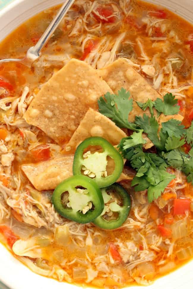 A white bowl filled with white chicken chili without beans. A spoon rests in the bowl.