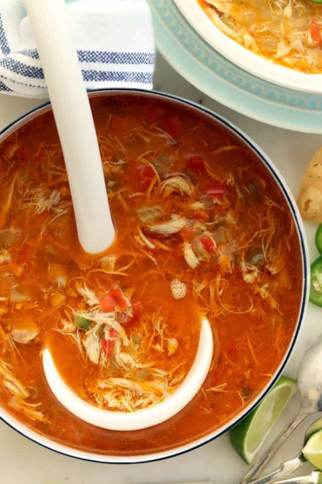A white pot filled with soup. A white ladle rests in the pot.