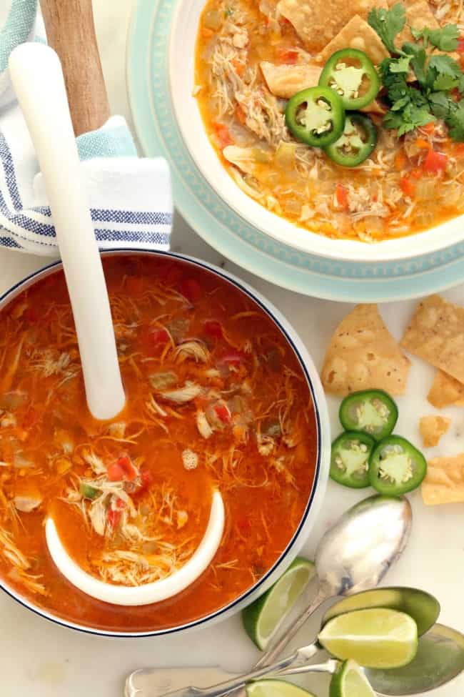 A white pot filled with chicken chili without beans. A ladle rests in the pot.