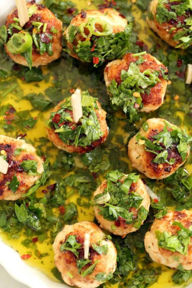 A shallow white tray filled with chicken chimichurri cocktail meatballs.