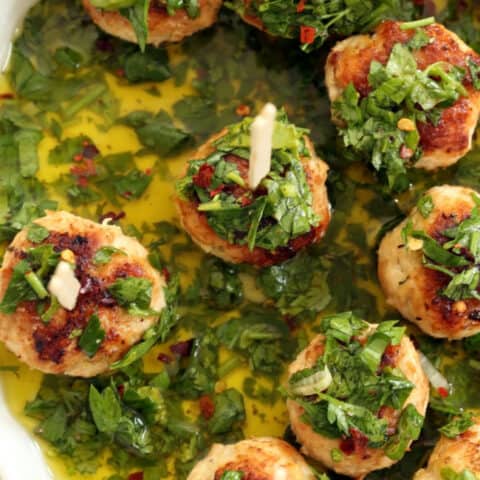 A shallow white tray filled with Chicken Chimichurri Meatballs,